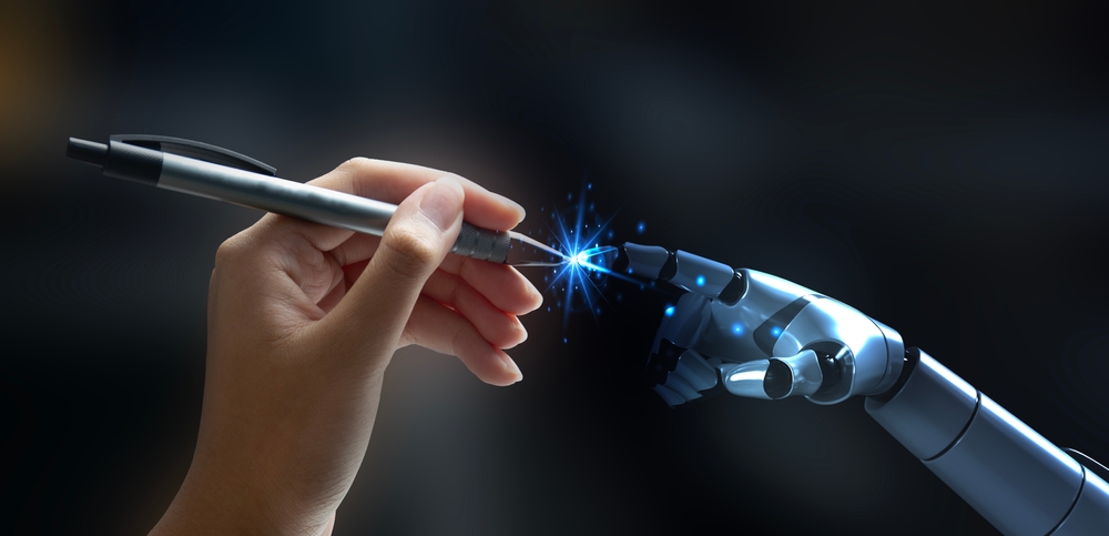 A human hand holding a pen receives it from a robotic hand, with a glowing blue light at the point of contact, symbolizing collaboration between humans and AI.