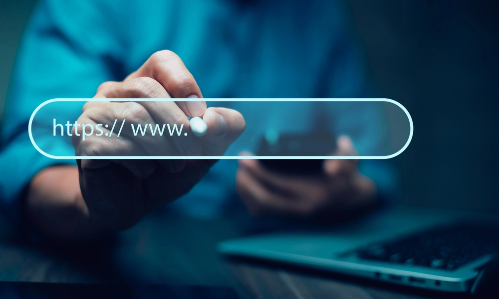 A person interacting with a browser bar showing 'https://' as part of a URL, emphasizing website navigation and security."
